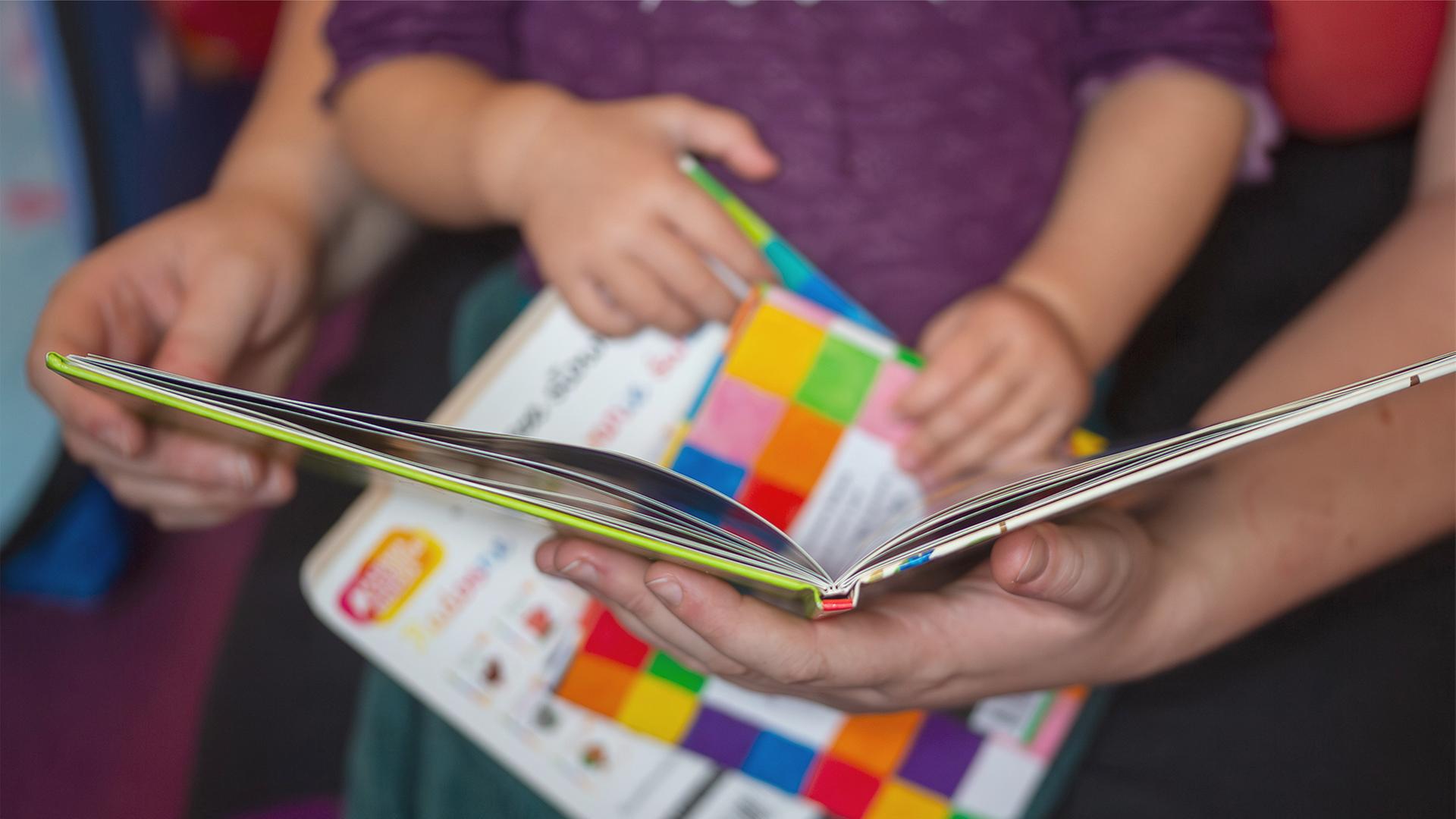 Eine Mutter liest ihrer kleinen Tochter aus einem Buch vor. | dpa
