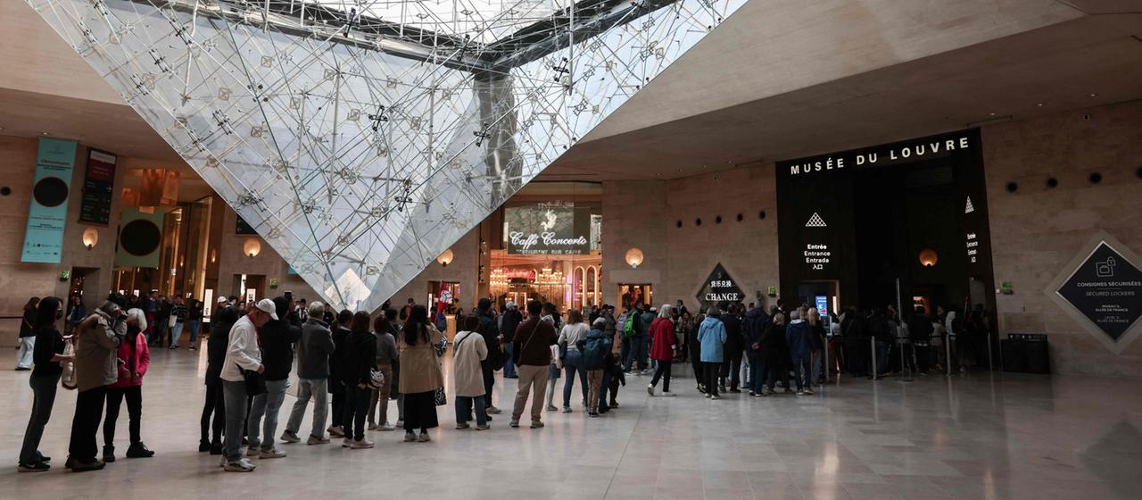 Besucher stehen am Eingang des Louvre-Museums an.