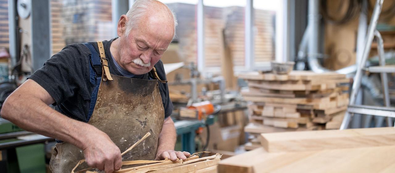 Ein älterer Mann bei der Holzverarbeitung in einer Werkstatt.