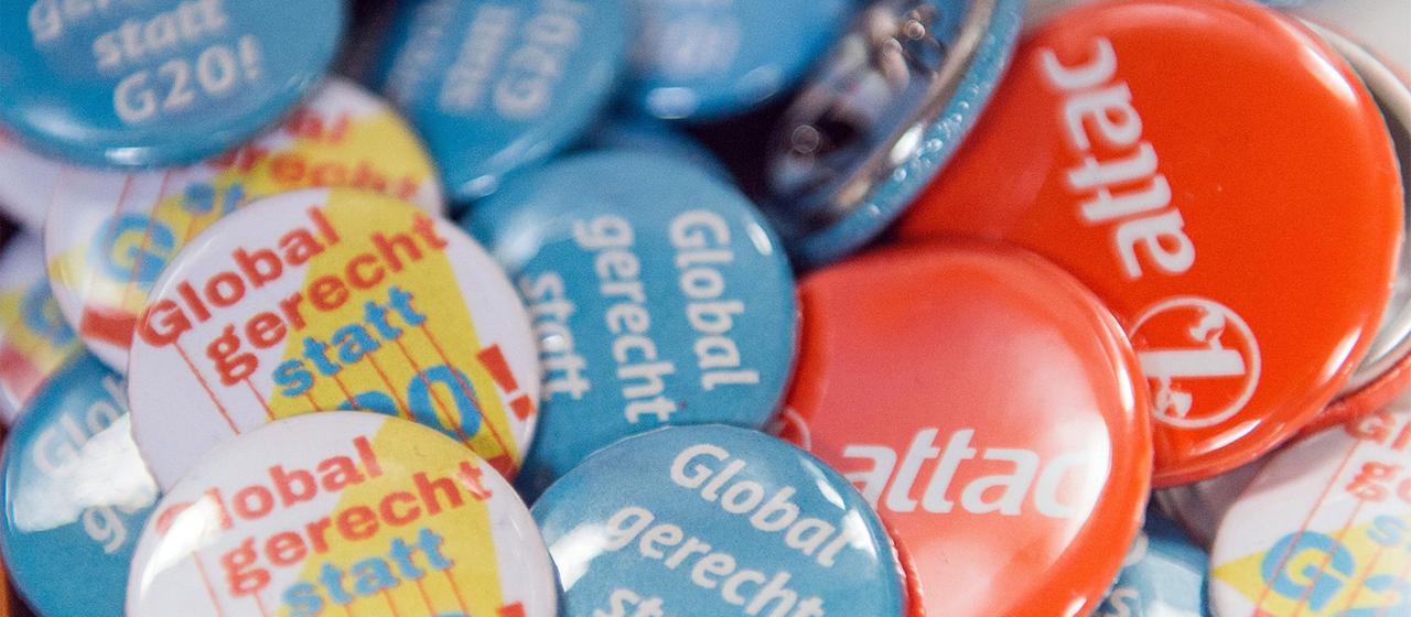 Unterschiedliche Buttons liegen beim Gipfel für globale Solidarität in Hamburg am Stand der Organisation Attac