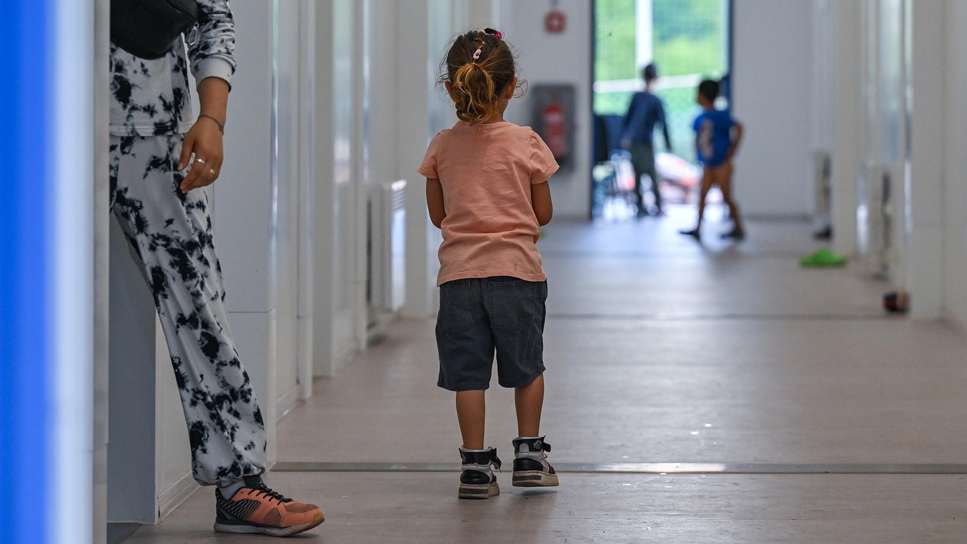 Ein kleines Mädchen steht auf dem Flur von Wohncontainern für Migranten. | dpa