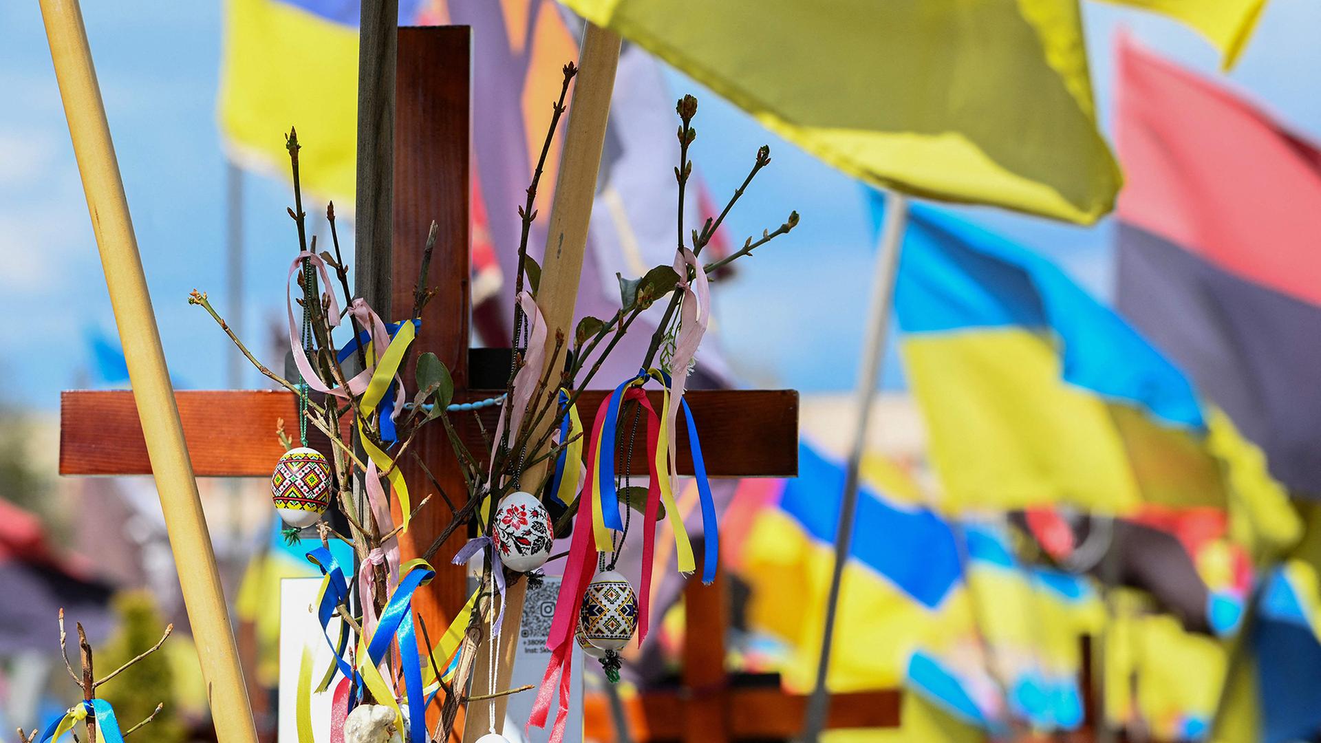 Hinter einem mit Ostereiern geschmückten Kreuz sind ukrainische Flaggen zu sehen. | AFP