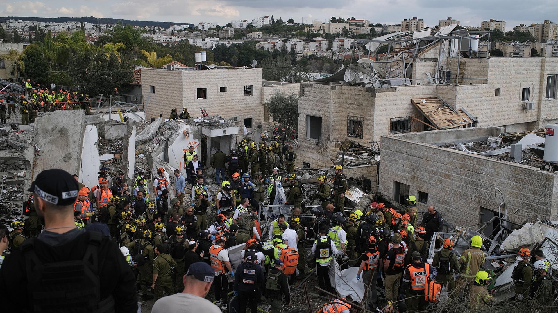 Rettungskräfte arbeiten bei durch eine Rakete zerstörten Häusern in Beit Schemesch. | Leo Correa/AP/dpa