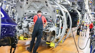 Ein Mitarbeiter montiert einen Porsche Macan im Werk Leipzig. 