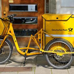 Ein gelbes Postfahrrad der Deutschen Post steht am 23.09.2024 vor einem Gebäude. (Quelle: Picture Alliance/Michael Bihlmayer)