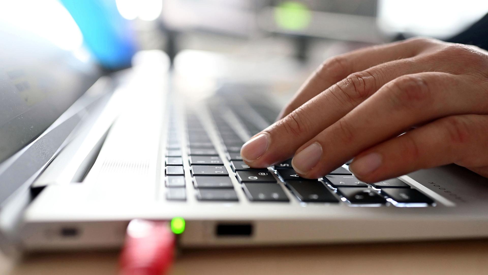 Eine Hand tippt auf der Tastatur eines Laptops. | picture alliance/dpa