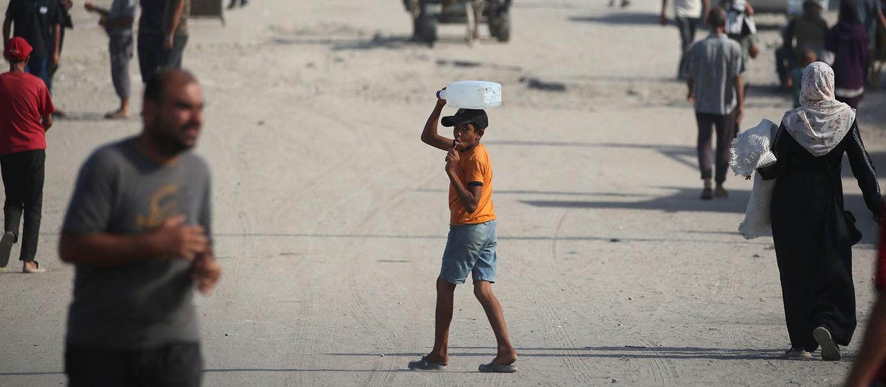 Ein Junge mit einem Wasserkanister auf einer belebten Straße im Gazastreifen