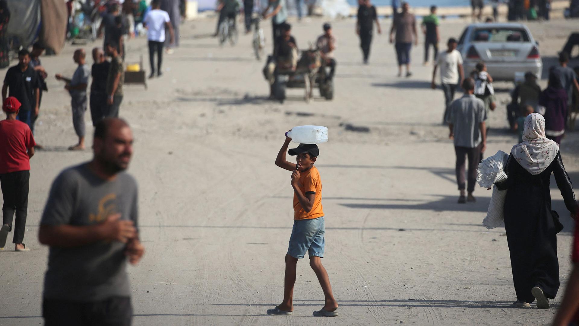 Ein Junge mit einem Wasserkanister auf einer belebten Straße im Gazastreifen | AFP