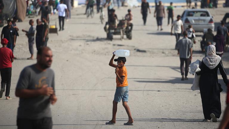 Ein Junge mit einem Wasserkanister auf einer belebten Straße im Gazastreifen