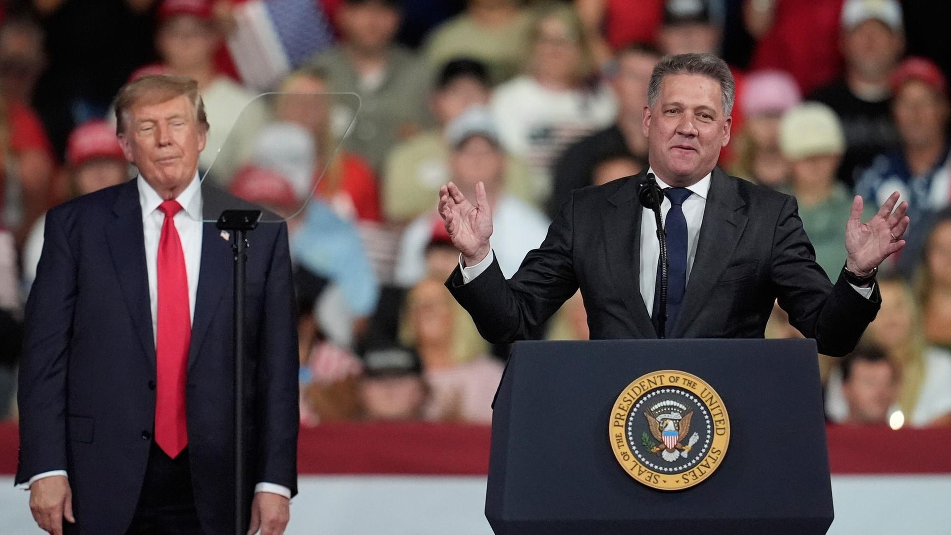 US-Präsident Donald Trump hört zu, während Gernot Döllner (r), Vorstandsvorsitzender der Audi AG, bei einer Wahlkampfveranstaltung im Guardian Centers of Georgia spricht.  | dpa Bildfunk, picture alliance/dpa/AP | Mike Stewart