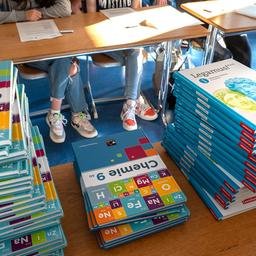 Schulbücher liegen auf einem Tisch in einem Klassenzimmer.