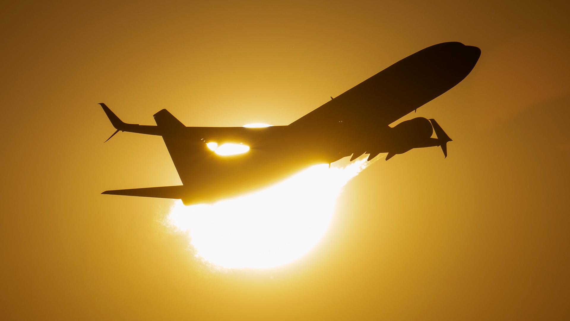 Ein Passagierflugzeug vor der untergehenden Sonne. | Boris Roessler/dpa