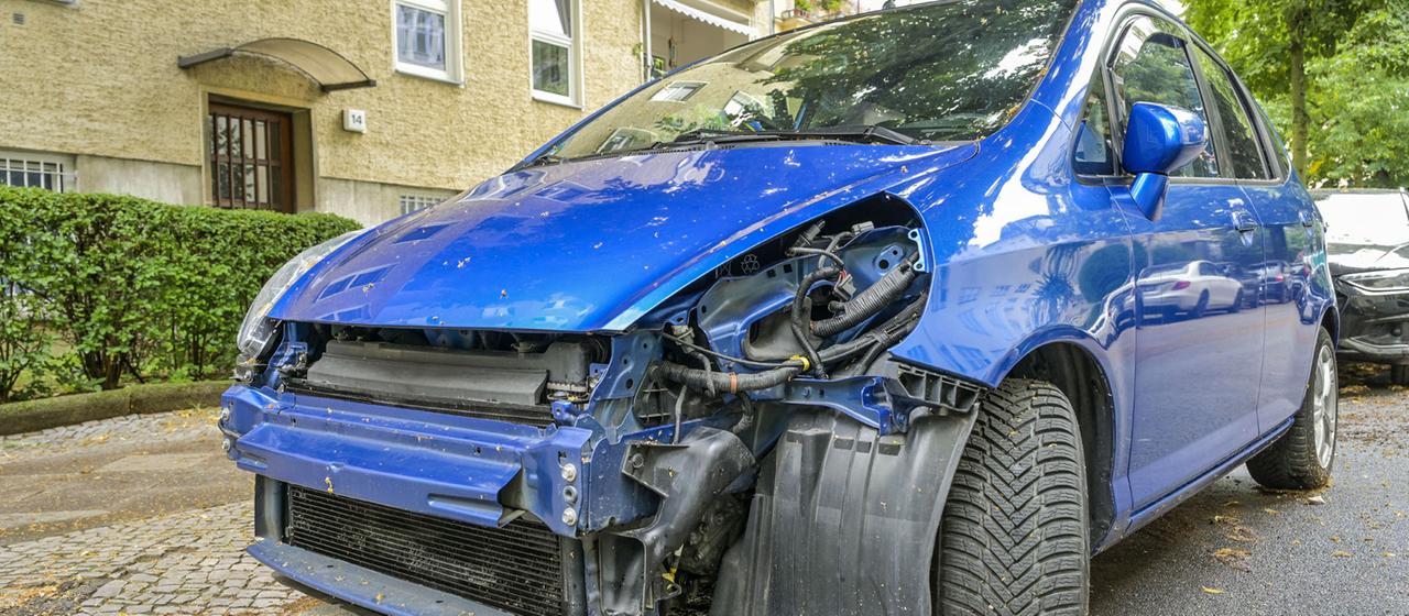 Ein stark beschädigter blauer PKW nach einem Unfall. 