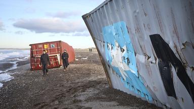 Menschen gehen neben mehrere Container, die an den dänischen Strand zwischen Tranum und Slettestrand angeschwemmt wurden.