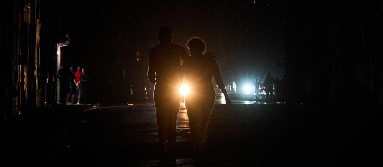 Menschen überqueren eine Straße während eines Stromausfalls in Havanna, Kuba.