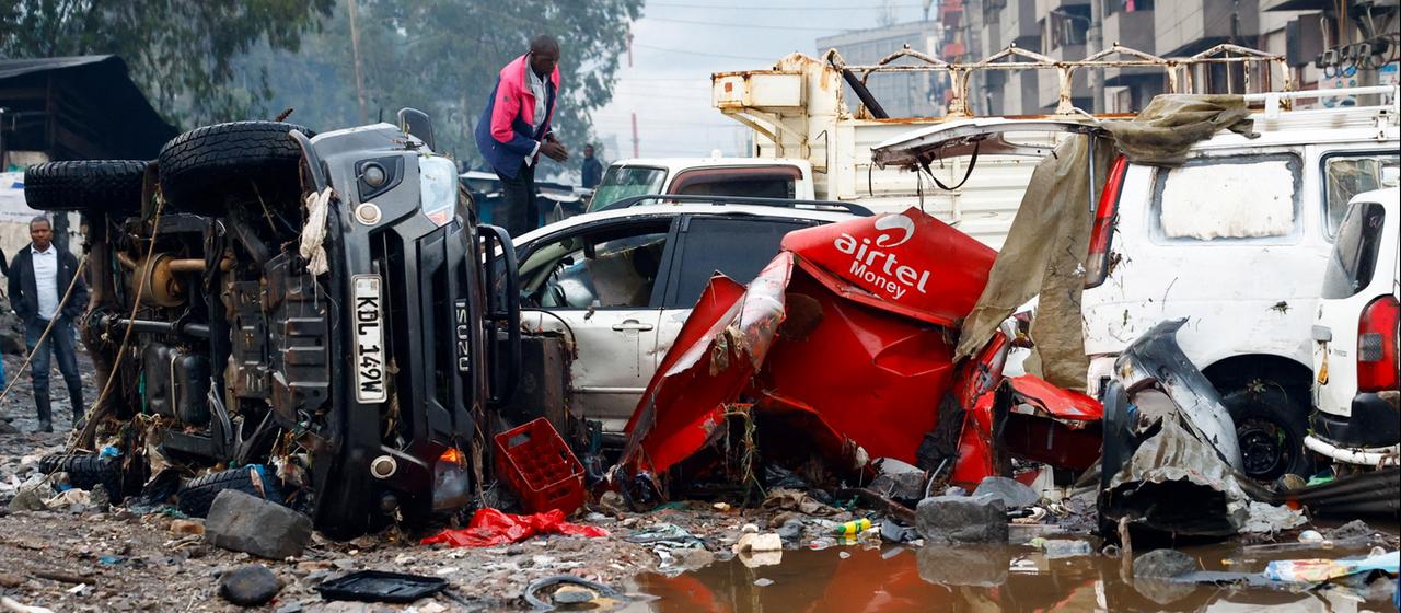 Ein Mann steht auf Trümmern von Fahrzeugen, die nach starken Regenfällen in Nairobi zerstört wurden.