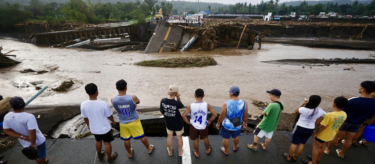 Menschen schauen auf eine durch den Sturm "Trami" zerstörte Brücke in der philippinischen Provinz Batangas.