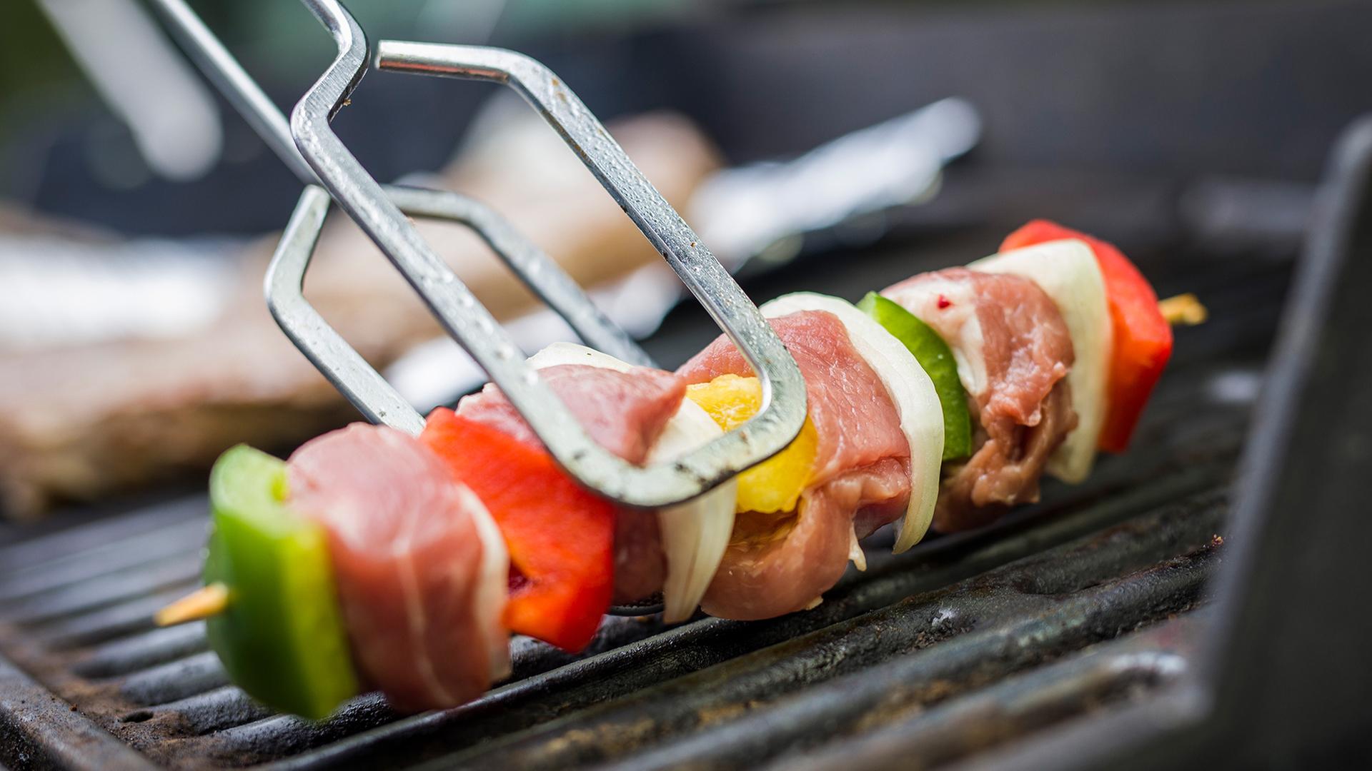 Ein Schaschlik-Spieß liegt auf einem Gasgrill.