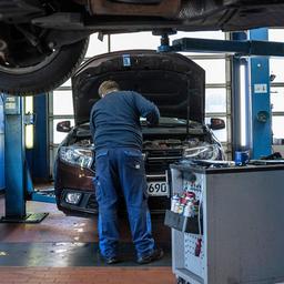 Ein Mechaniker blickt in den Motorraum eines Autos in einer Kfz-Werkstatt.