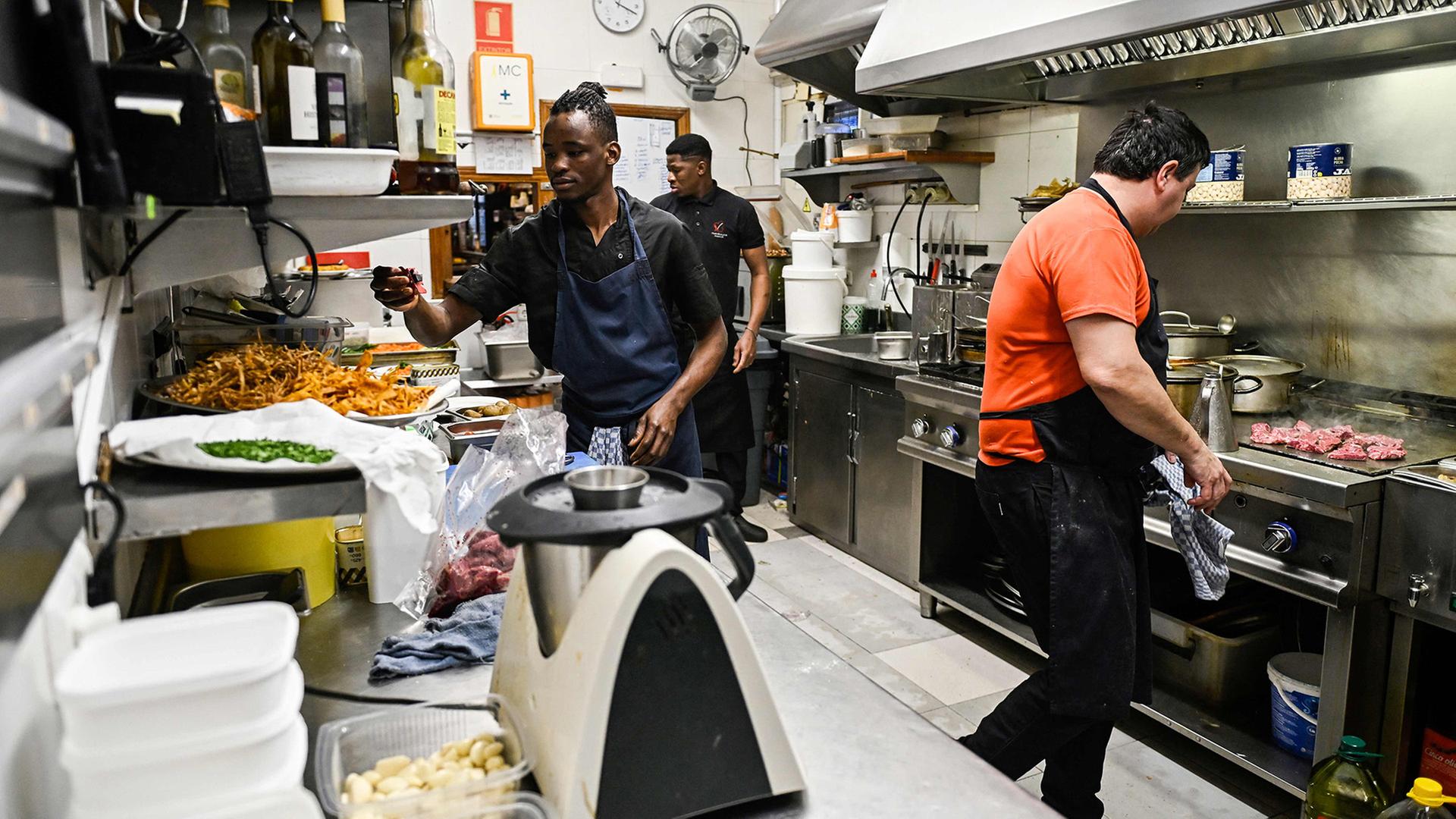 Drei Männer arbeiten in einer Restaurantküche. | AFP