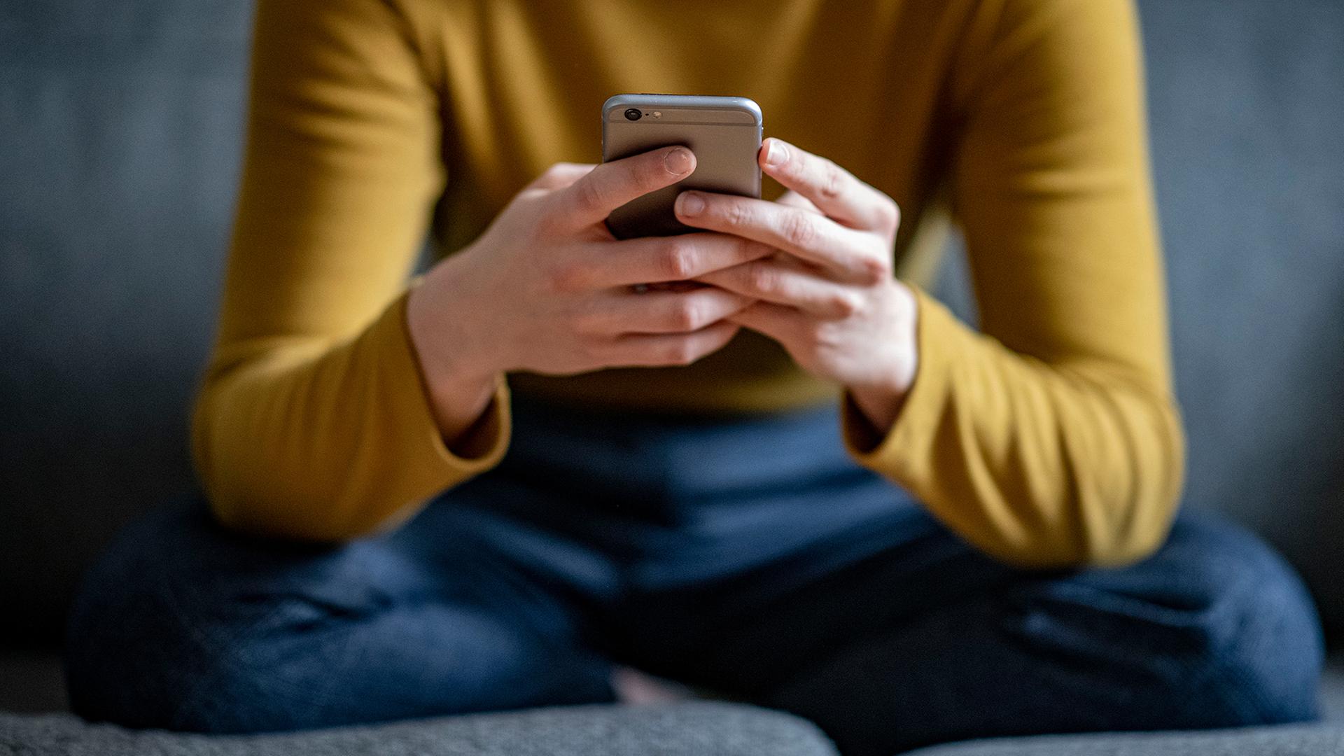 Eine junge Frau hält ein Smartphone in der Hand. | dpa