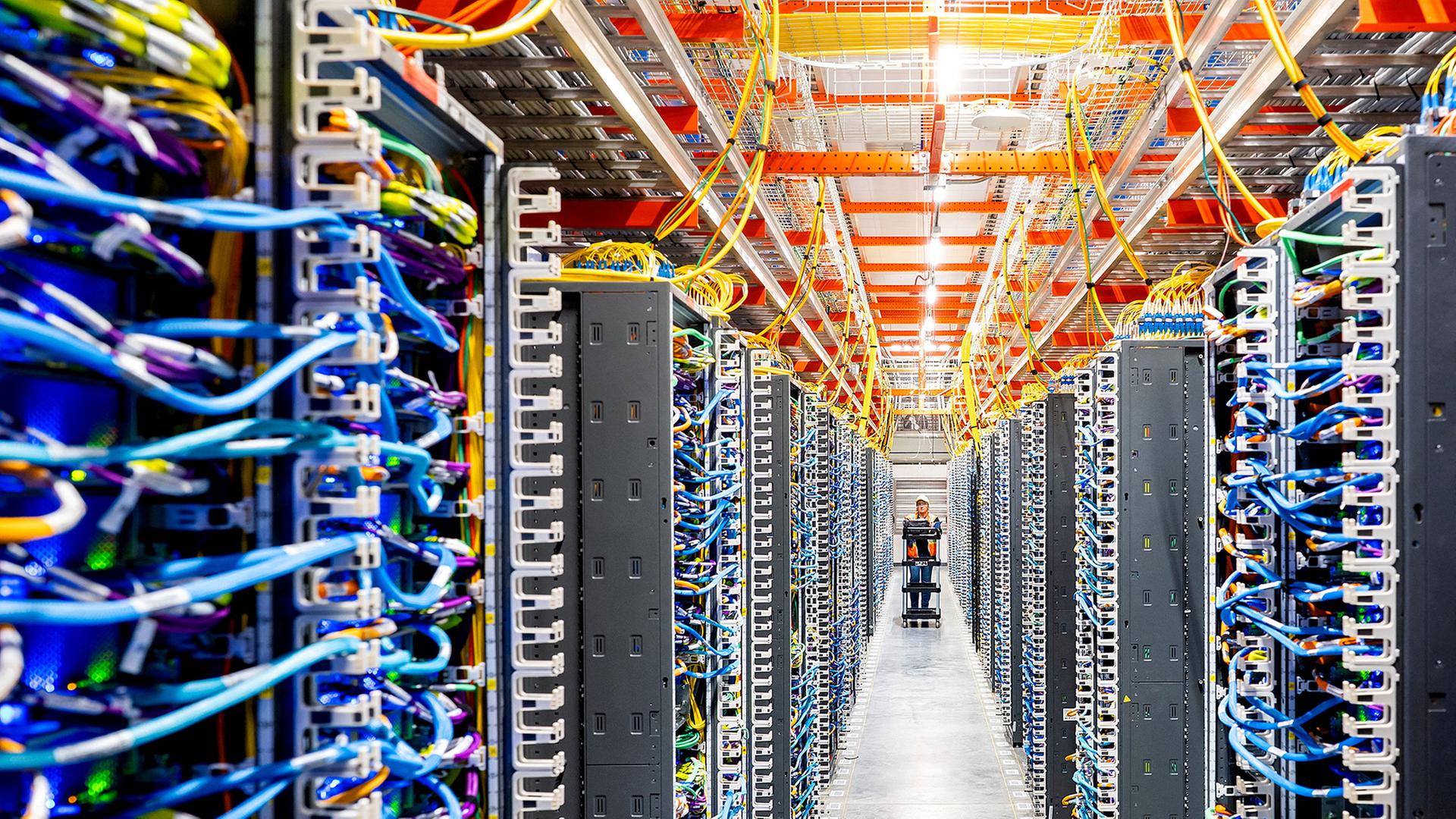 Ein Mitarbeiter geht durch einen langen Gang eines Data-Centers. | REUTERS