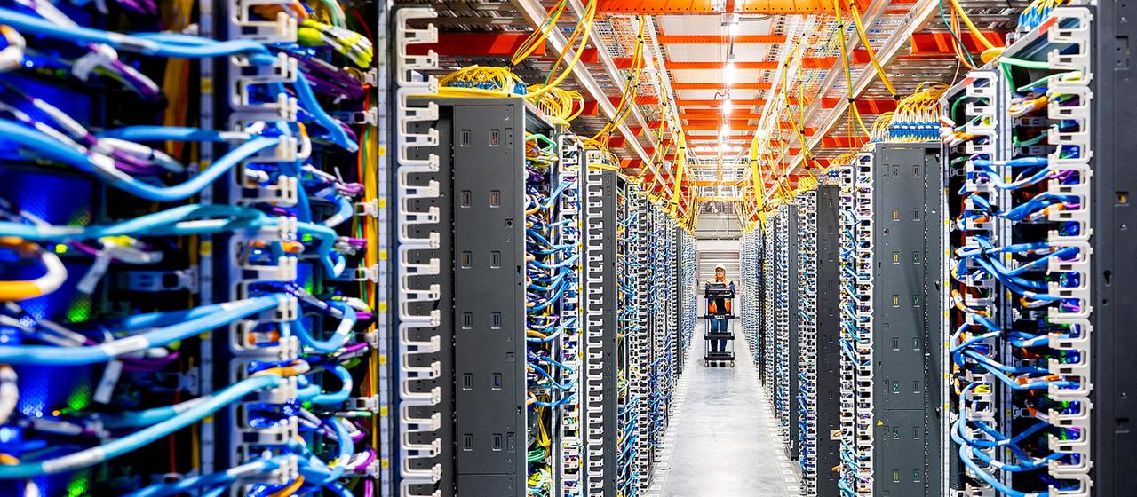 Ein Mitarbeiter geht durch einen langen Gang eines Data-Centers.