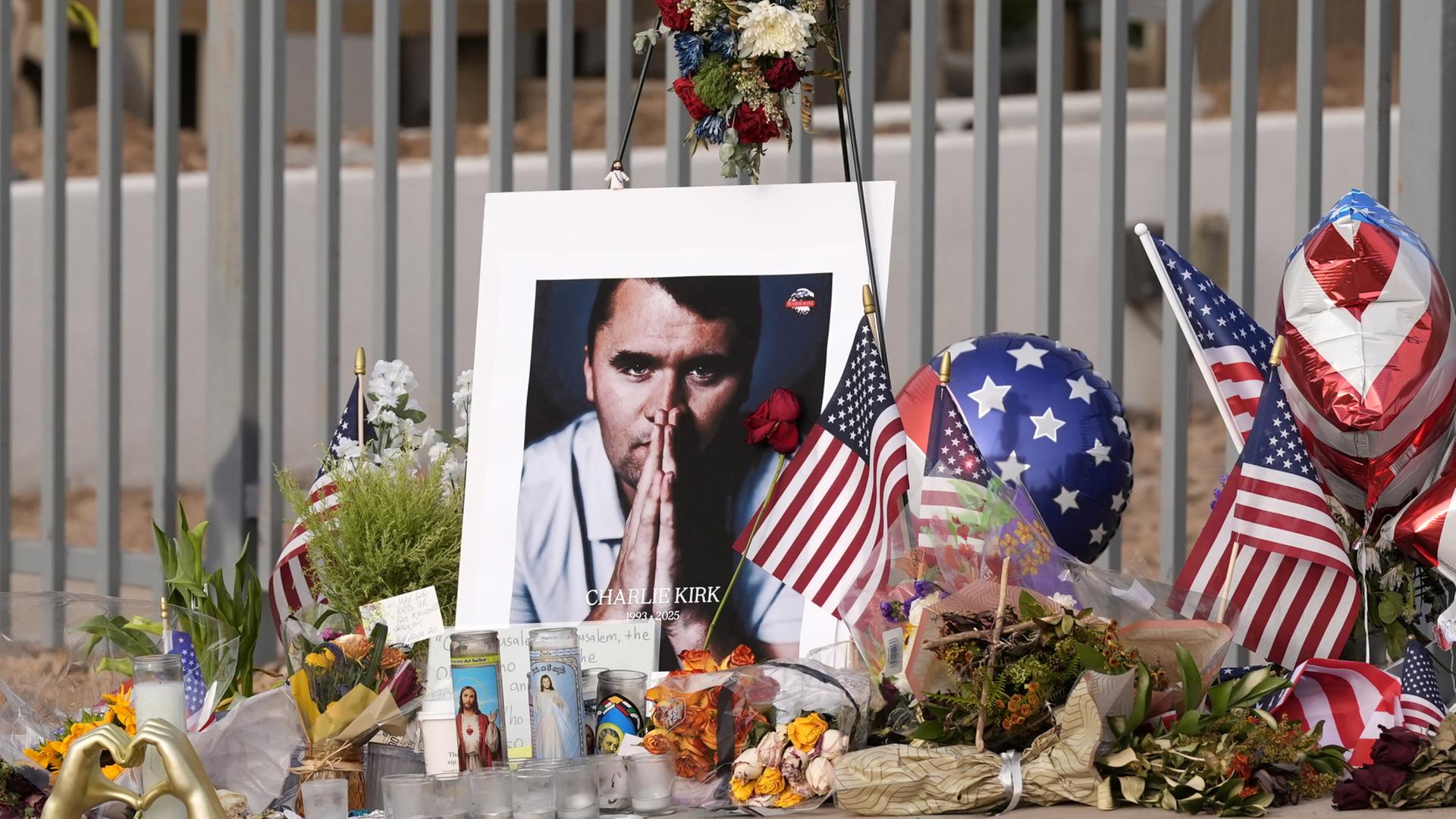 Neben einem Foto von Charlie Kirk sind Blumen, Kerzen, Flaggen und Ballons zu sehen. | AP