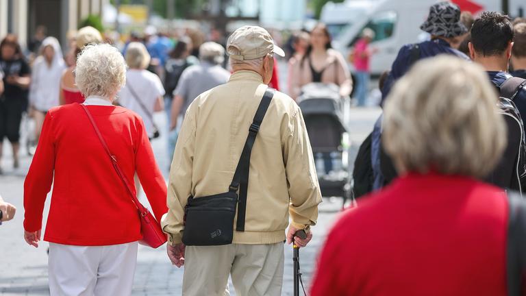 EIn älteres Paar geht durch die Innenstadt.