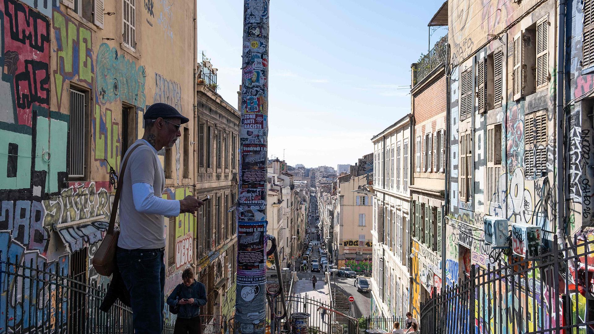 Zwei Personen in einer mit Graffiti bedeckten Gasse in Marseille. | AFP