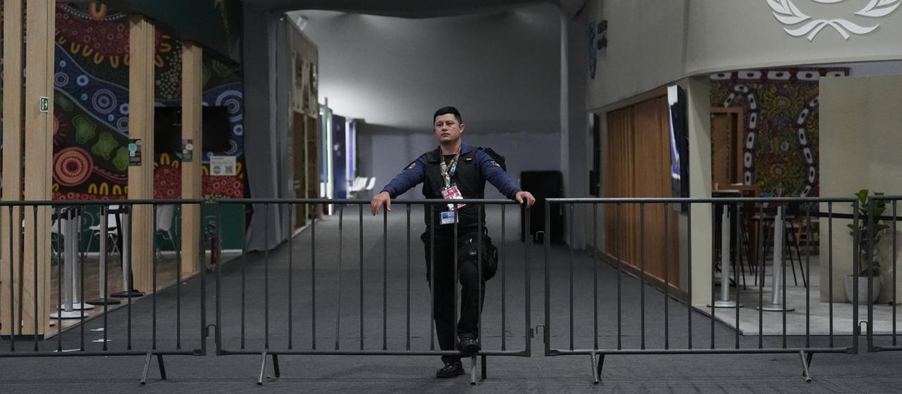 EIn Wachmann steht an einer Absperrung auf dem Gelände der Weltklimakonferenz.