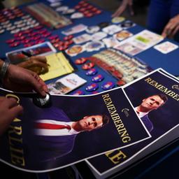 Plakate zur Erinnerung an den getöteten Charlie Kirk liegen auf einem Tisch.