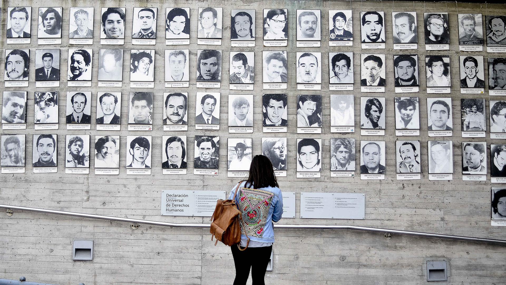 Eine Frau schaut auf Bilder der Opfer der chilenischen Militärdiktatur von Augusto Pinochet. | picture alliance/dpa