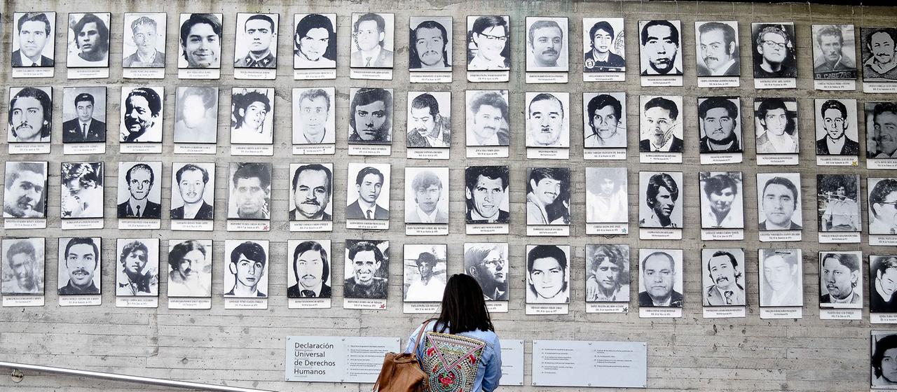 Eine Frau schaut auf Bilder der Opfer der chilenischen Militärdiktatur von Augusto Pinochet.
