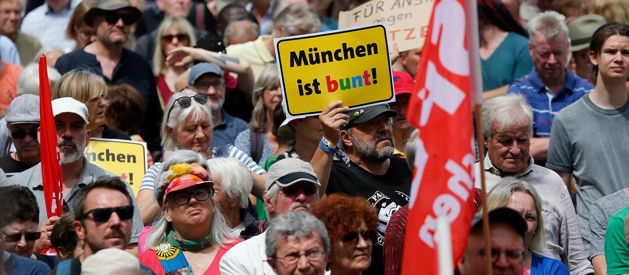Ein Teilnehmer einer Demo trägt ein Schild mit Aufschrift "München ist bunt!".