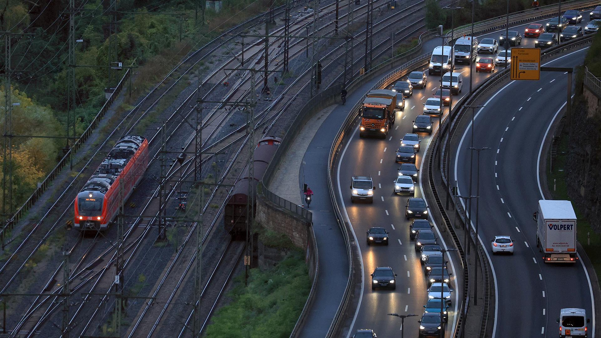 Autos fahren am frühen Morgen neben einer Bahnlinie. | dpa