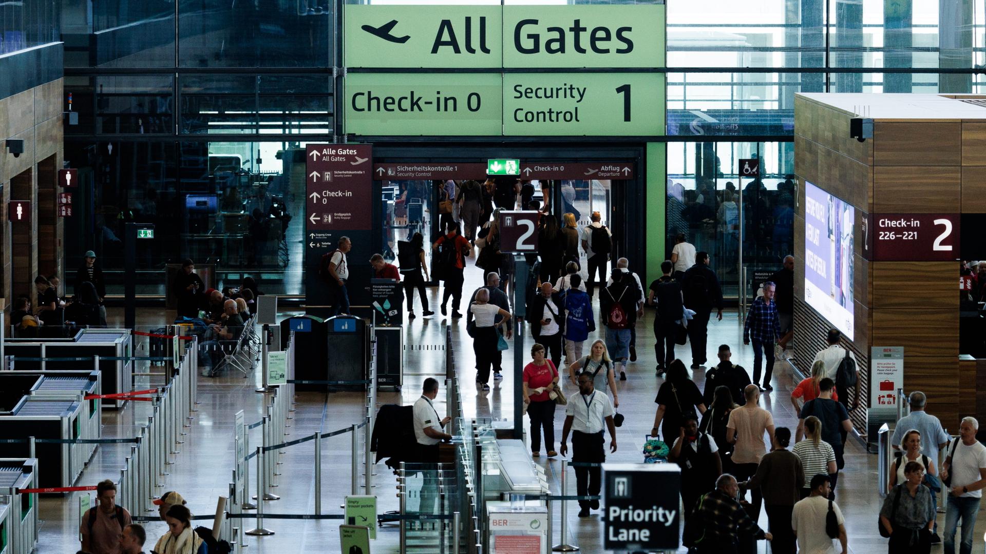 Passagiere sind in einem Terminal am Berliner Flughafen BER unterwegs. | dpa