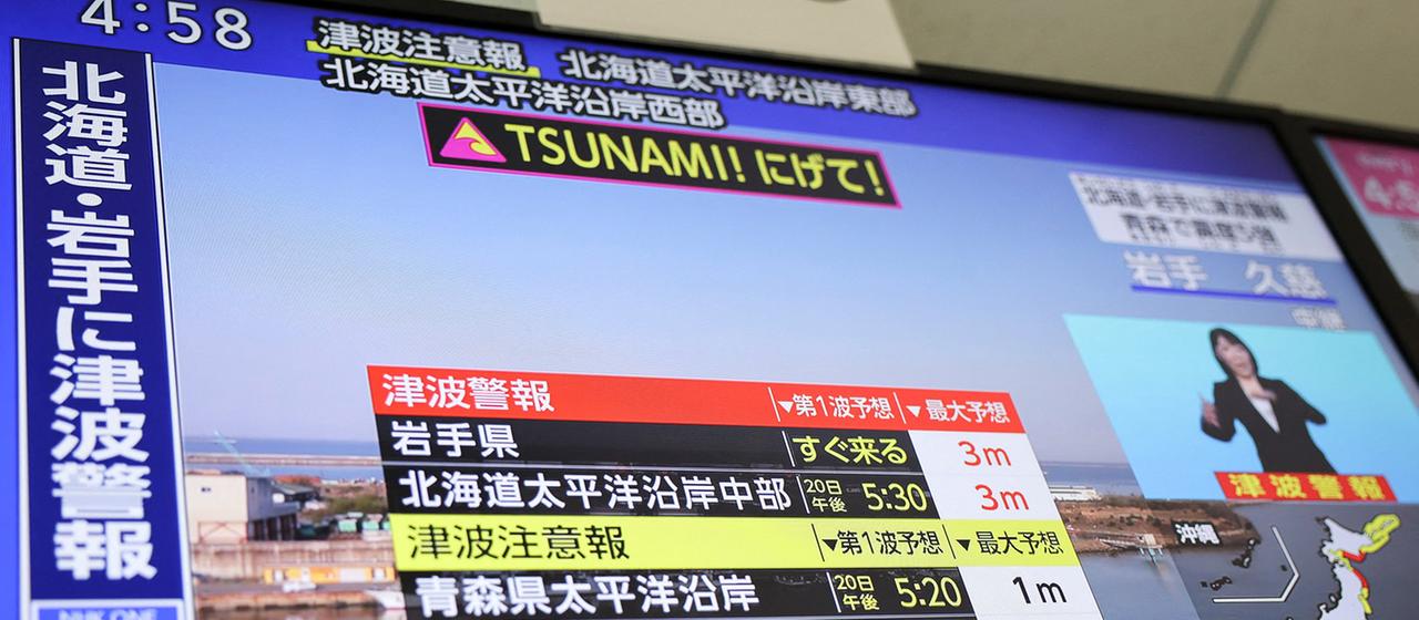 Ein Fernsehbildschirm zeigt einen Nachrichtenbericht aus Japan über die Tsunami-Warnung nach einem Erdbeben.
