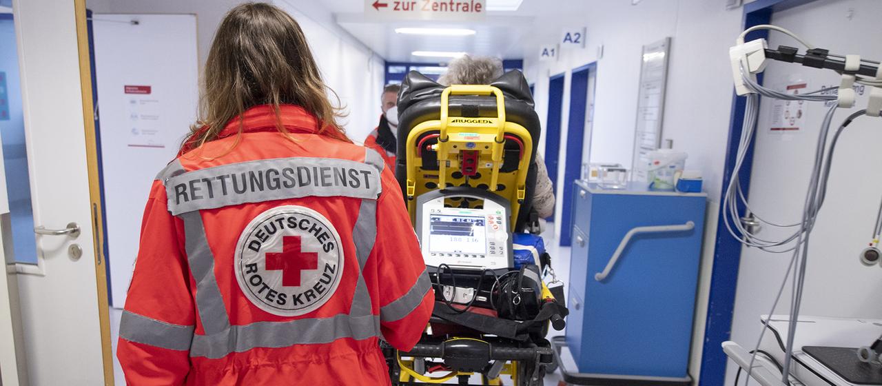 Eine Notfallsanitäterin schiebt eine Seniorin nach einem Schlaganfall auf einer Trage in die Notaufnahme eines Krankenhauses.