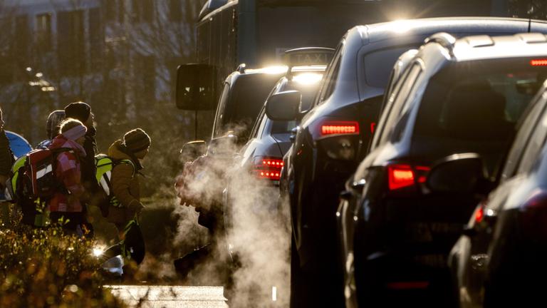 Schulkinder neben einer befahrenen Straße