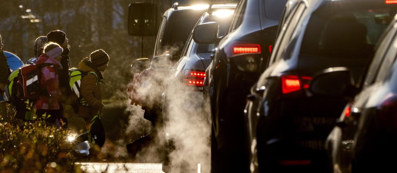 Schulkinder neben einer befahrenen Straße