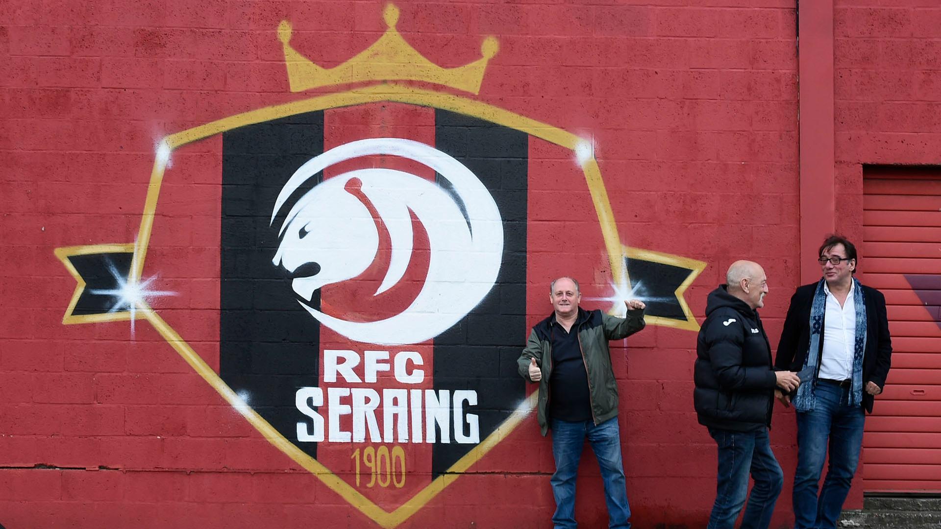 Fans posieren vor einem Logo des belgischen Fußballvereins RFC Seraing. | picture alliance/dpa/BELGA