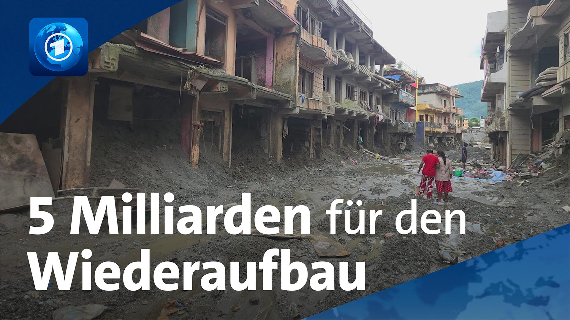 Zwei Personen stehen auf einer von Schlamm und TrÃ¼mmern bedeckten StraÃe zwischen zerstÃ¶rten GebÃ¤uden | ARD-aktuell