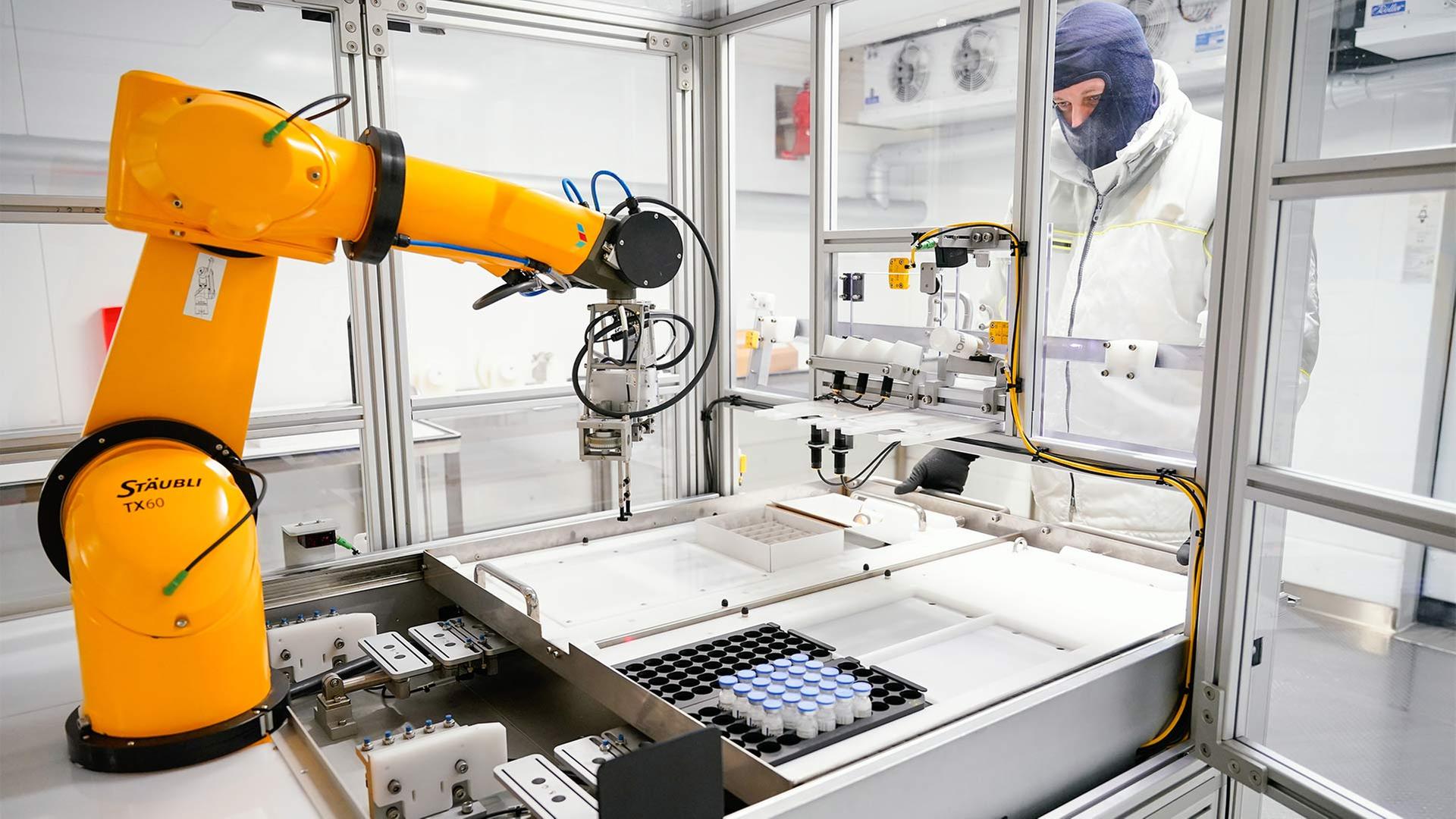 Mitarbeiter von Roche Diagnostics an einem Roboter zur Phiolen-Etikettierung. | picture alliance/dpa