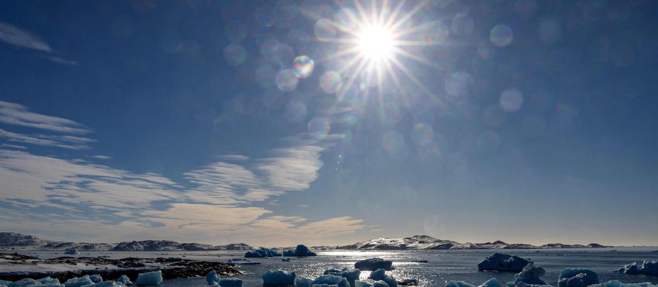 Die Sonne scheint auf im arktischen Meer treibende Eisschollen.