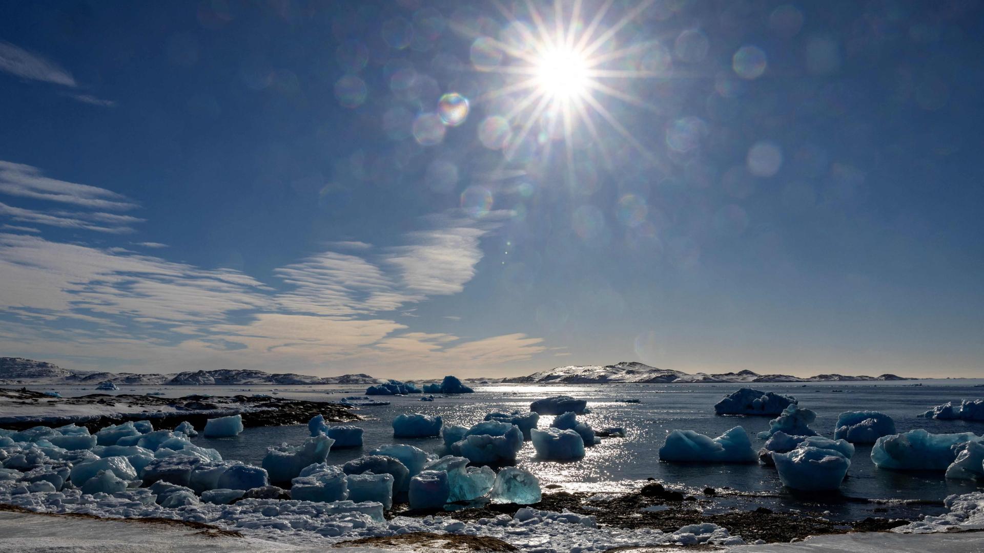 Die Sonne scheint auf im arktischen Meer treibende Eisschollen. | AFP