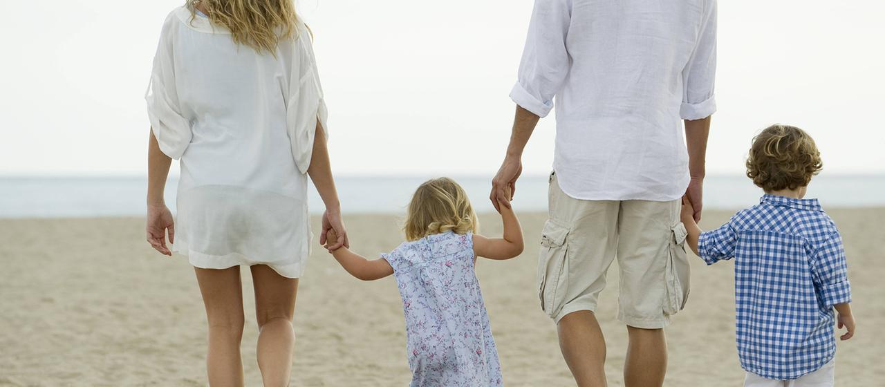 Eine Familie geht am Strand spazieren | imago/PhotoAlto Eine Familie geht am Strand spazieren
