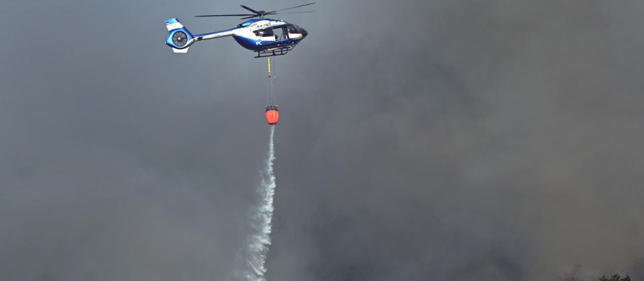 Ein Polizeihubschrauber unterstützt die Löscharbeiten beim Waldbrand im Hürtgenwald