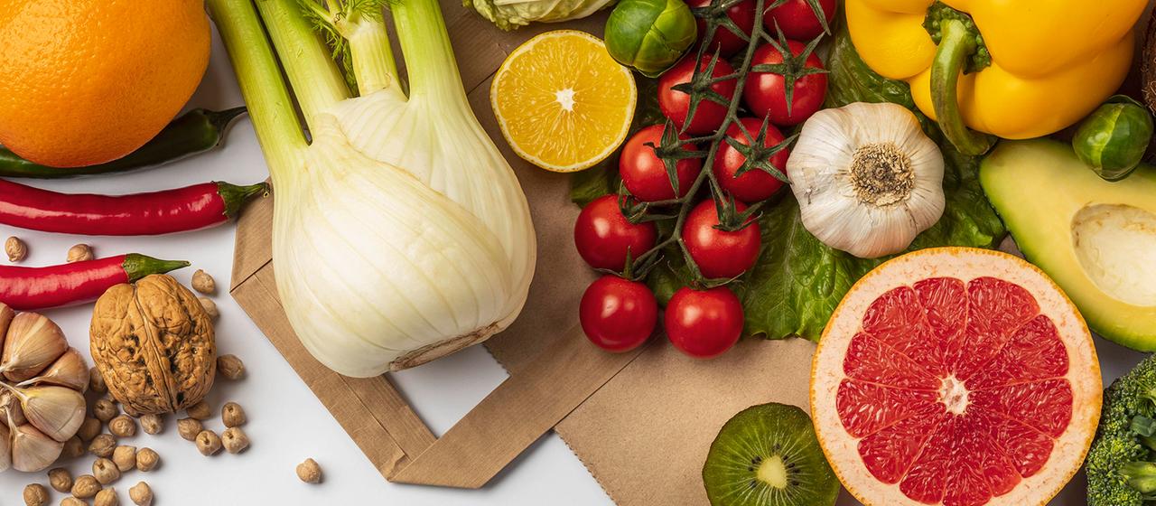 Gemüse, Obst und Hülsenfrüchte liegen auf einer Papiertüte.