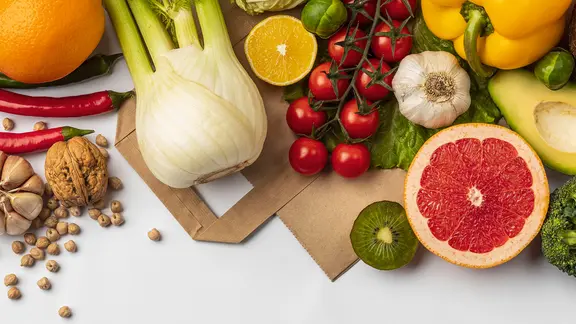 Gemüse, Obst und Hülsenfrüchte liegen auf einer Papiertüte.